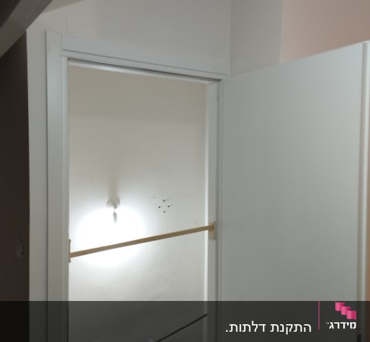 דלת לבנה פתוחה עם ידית מתכת כסופה